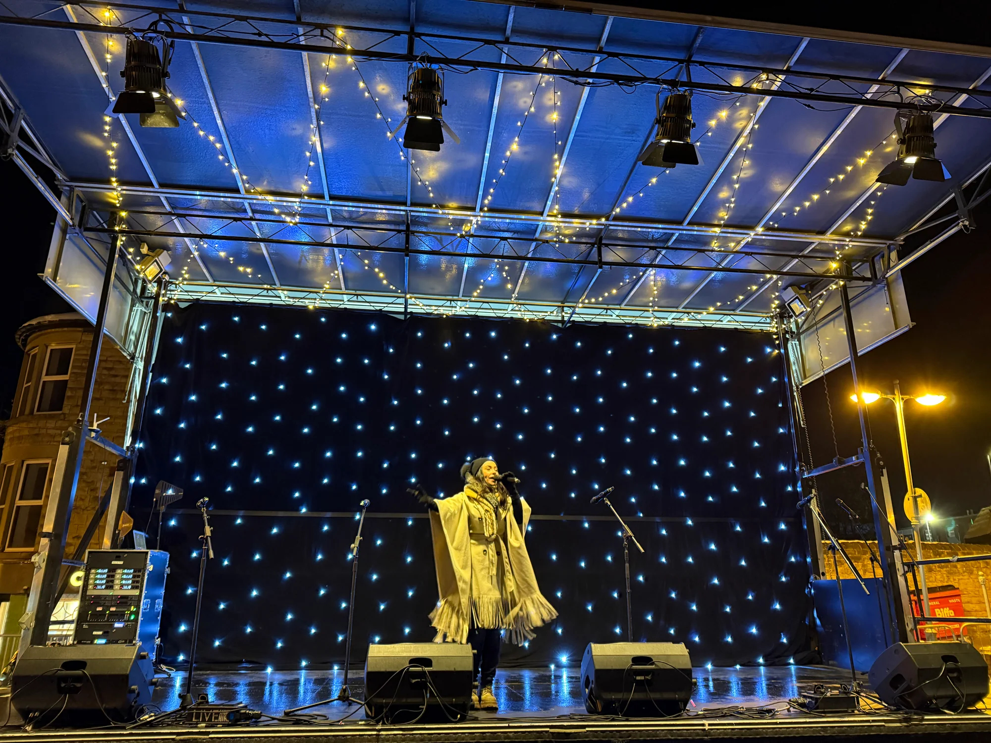 Singer performing on the 8m x 4m Christmas light switch-on stage with fairy lights and starcloth