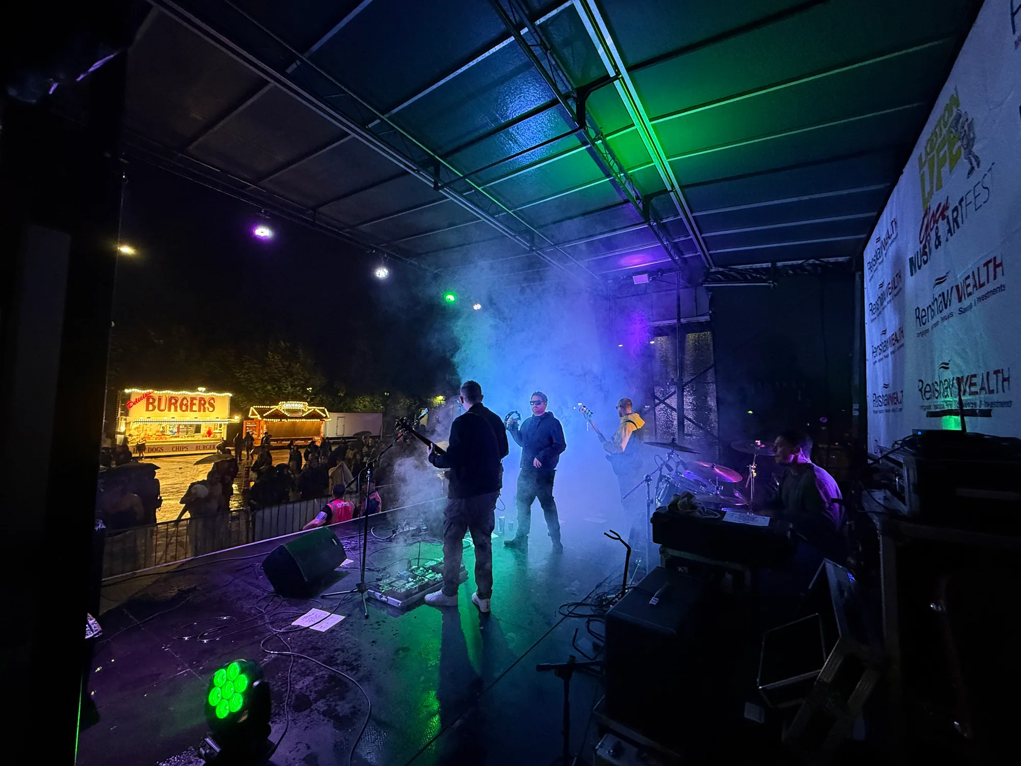 Band performing on the covered main stage during a wet Ilkeston Glow Festival