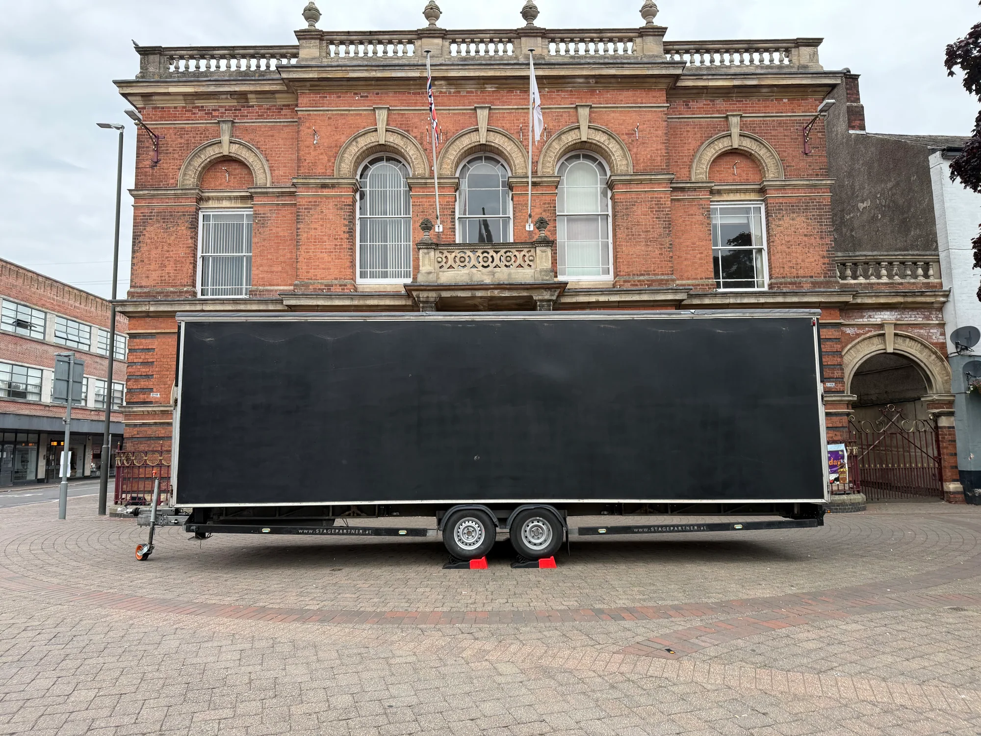 Folded trailer stage positioned between the kerbs in Ilkeston Market Place before setup