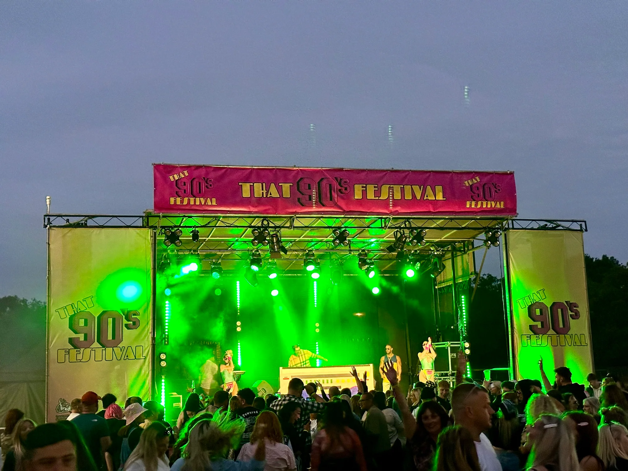 DJ and performers on the green-lit That's 90s Festival stage in 2024