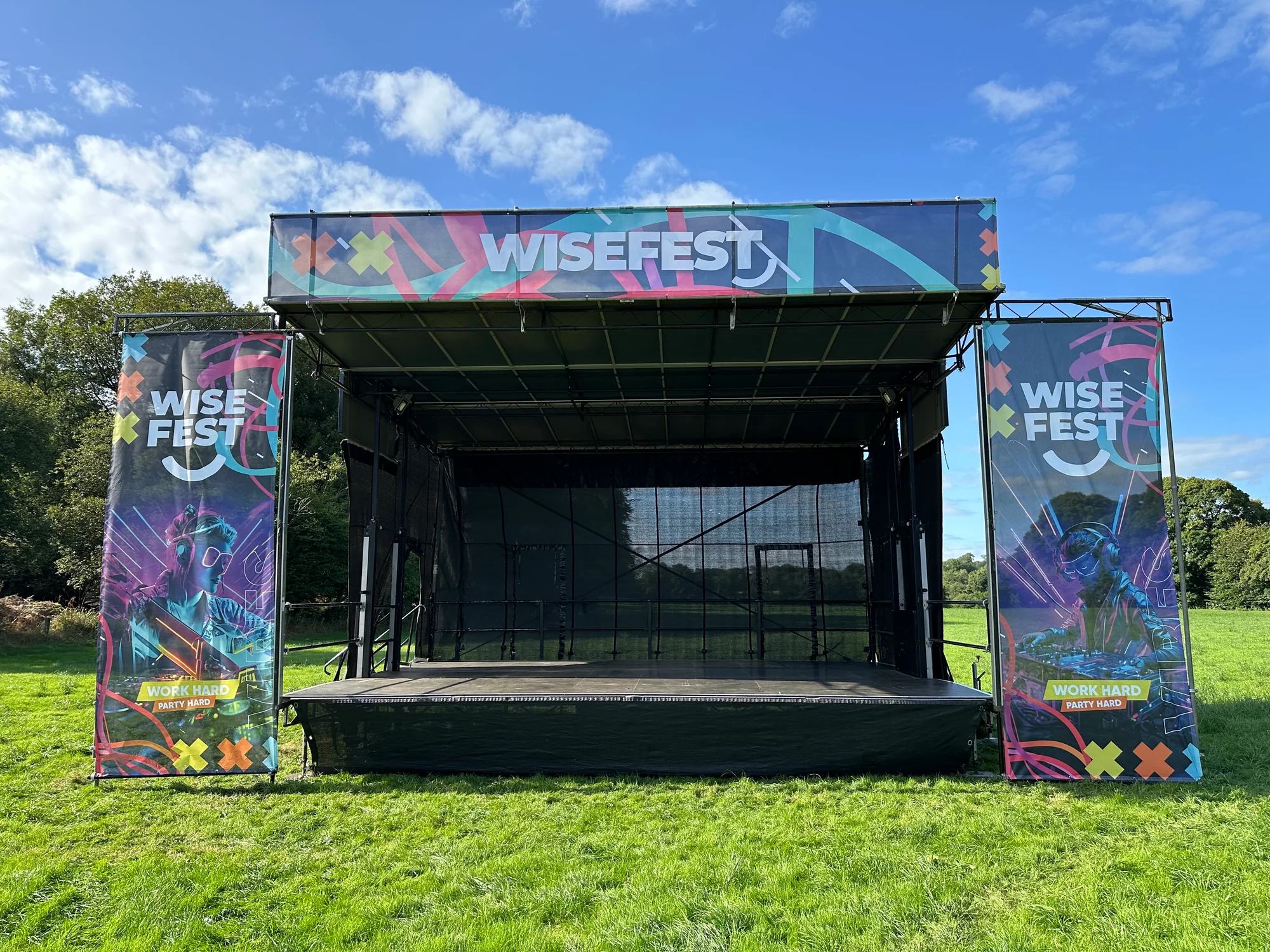 Completed 8m x 6m WiseFest stage with full top and side branding in a grass field