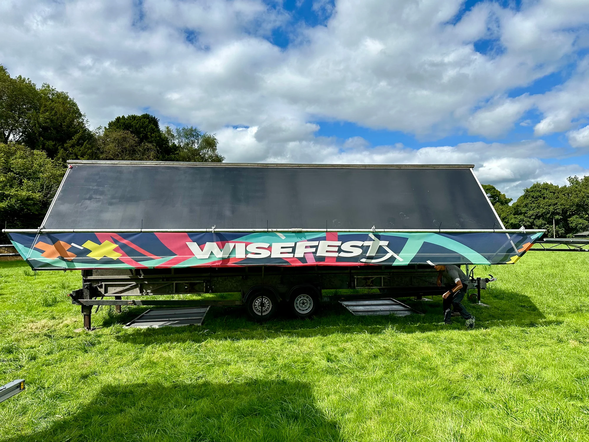 WiseFest trailer stage with its roof partly lowered while the top branding is installed