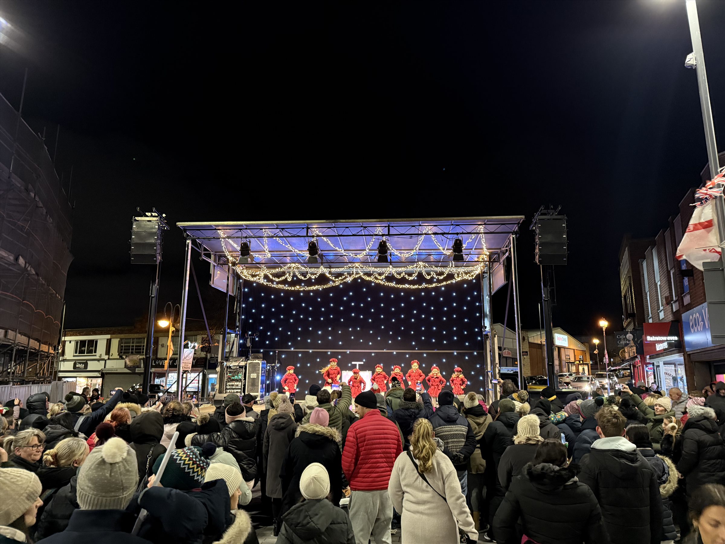 Christmas light switch-on audience watching performers on the covered trailer stage