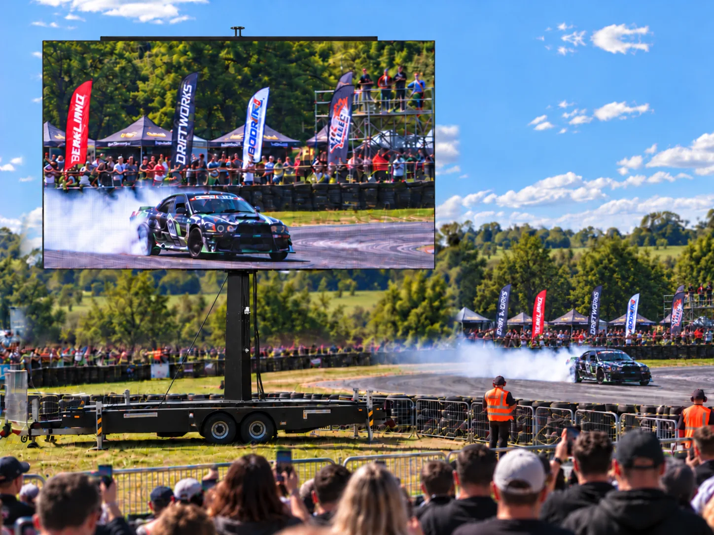 Illustration of a large outdoor screen beside a motorsport event