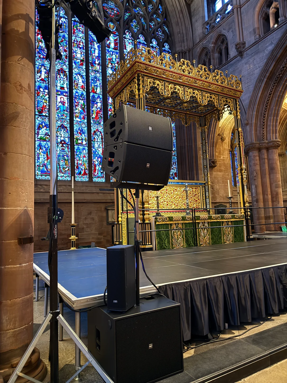 Floor-stack PA speakers and subwoofer beside a stage
