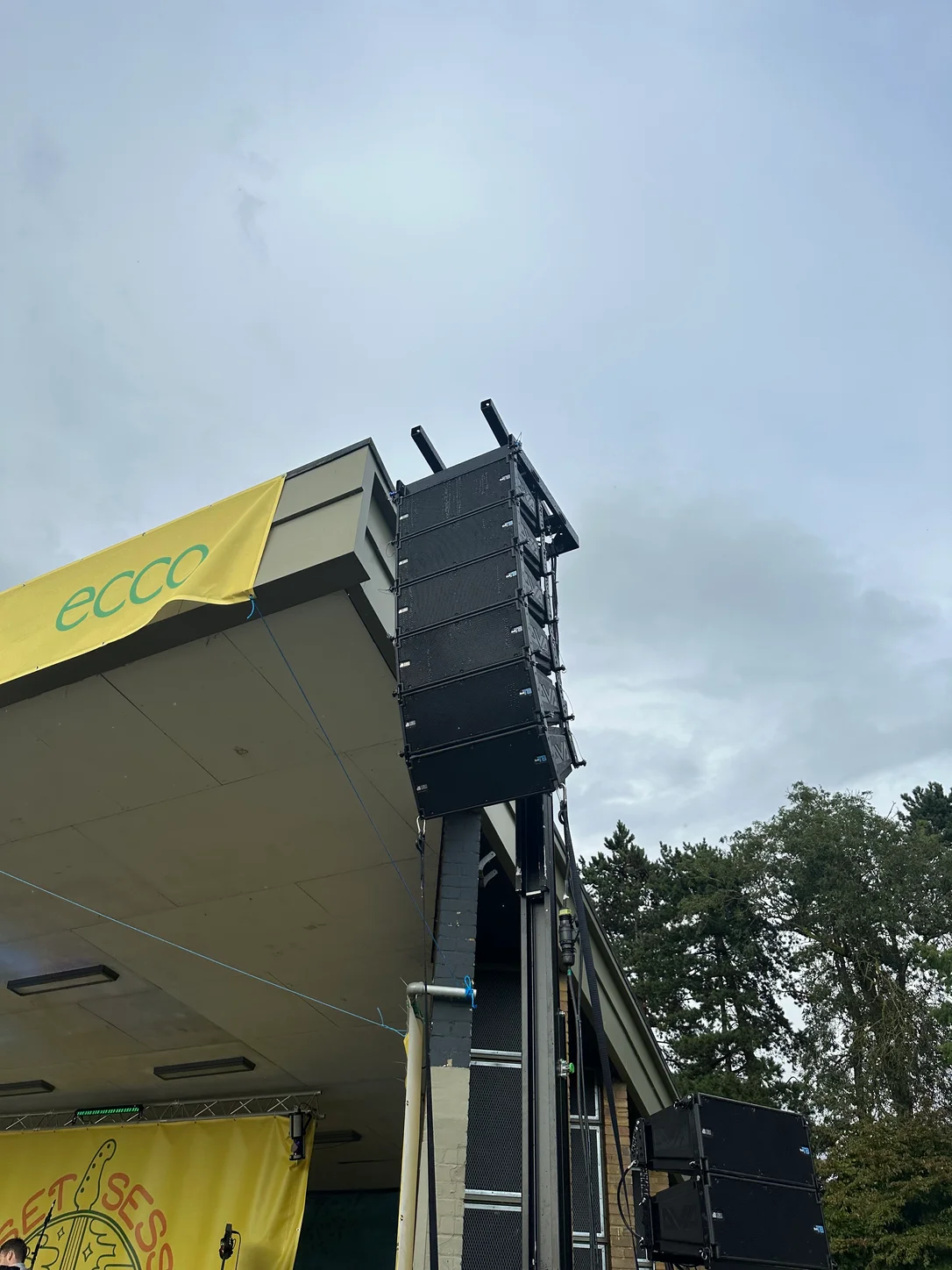 Flown PA array beside an outdoor stage